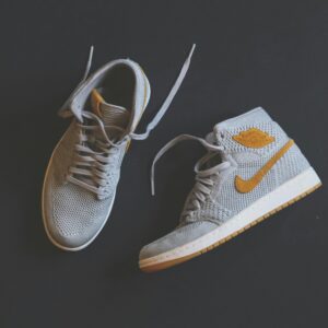 Close-up of fashionable gray and orange high-top sneakers displayed against a minimal background.