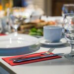 Close-up of an elegant dining table set with glassware, silverware, and red napkins in a restaurant setting.