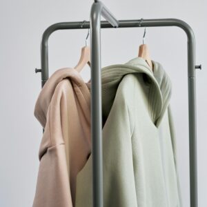 Two pastel hoodies on hangers against a simple backdrop, showcasing modern minimalist style.
