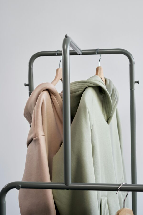 Two pastel hoodies on hangers against a simple backdrop, showcasing modern minimalist style.