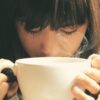 Woman savoring the aroma of a hot coffee cup in a cozy setting.