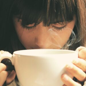 Woman savoring the aroma of a hot coffee cup in a cozy setting.