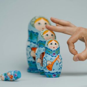 A close-up of traditional Russian nesting dolls being playfully arranged by a hand.