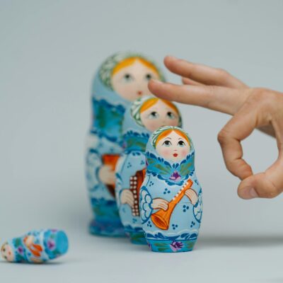 A close-up of traditional Russian nesting dolls being playfully arranged by a hand.