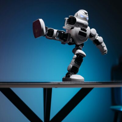 A modern robot toy balancing dynamically on one leg, set against a blue gradient background.