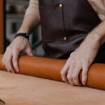 Close-up of hands working with leather, showcasing craftsmanship in an artisan workshop.