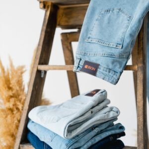Showcase of folded and hanging denim jeans on a wooden ladder, fashion display concept.