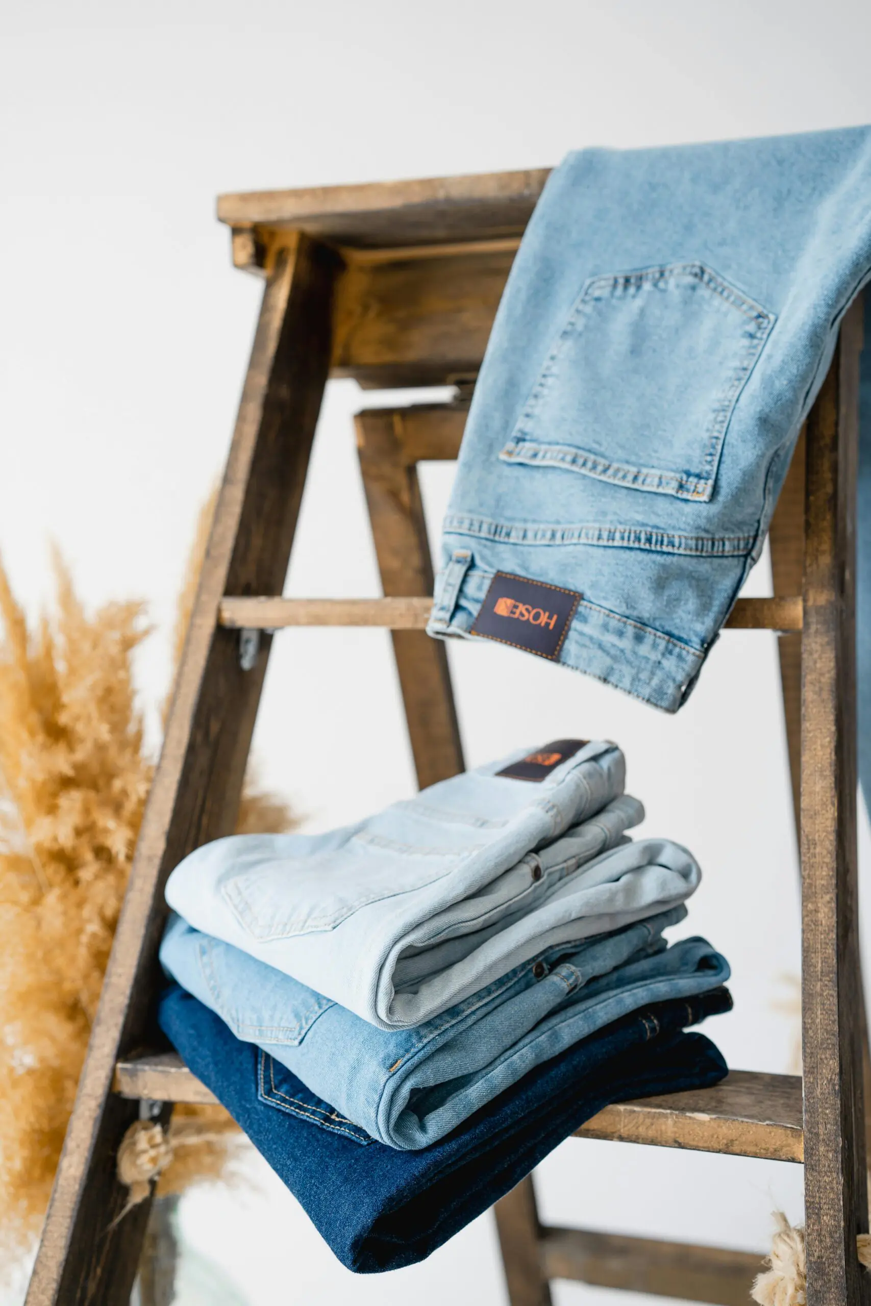 Showcase of folded and hanging denim jeans on a wooden ladder, fashion display concept.