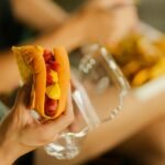 Close-up of a hot dog with mustard and ketchup held in hand, perfect street food meal.