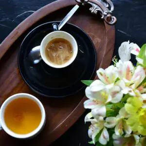 Top view of coffee and tea cups on a wooden tray with fresh Alstroemeria flowers.